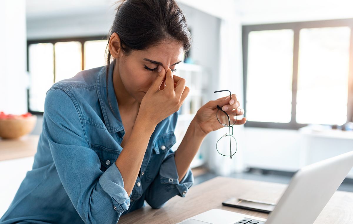 Woman working from home on a laptop, looking tired and fatigued